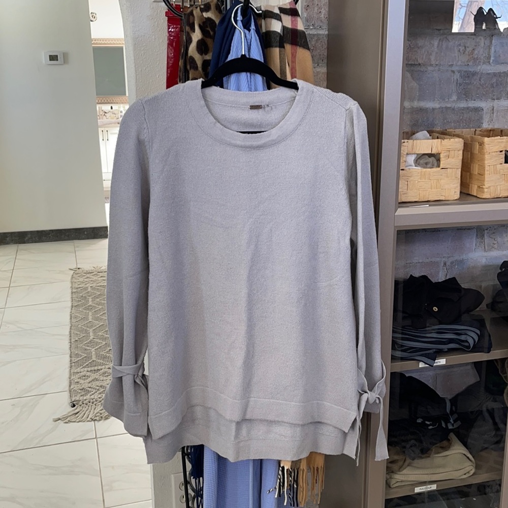 Grey sweater with tied sleeves. Can be tied in now or knot.